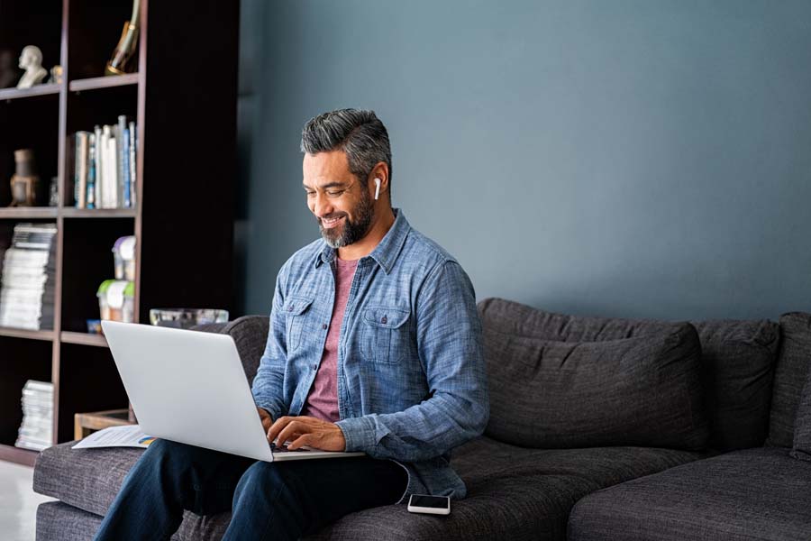 Man working on laptop on couch at home