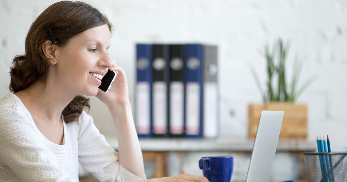 Smiling woman at desk on phone