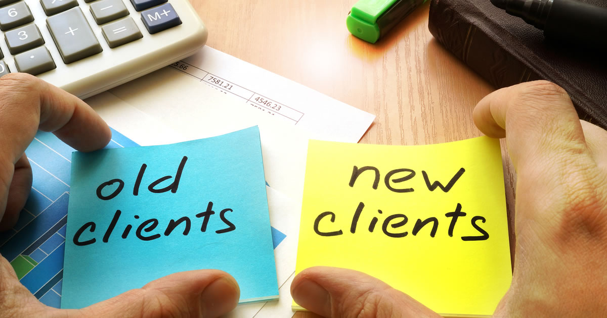 Hands on a desk holding side-by-side sticky notes with the words old clients written on the first one and new clients on the second