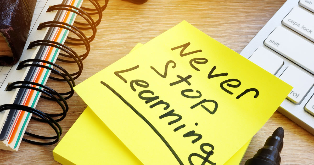 Close-up of desk with words Never Stop Learning written on sticky note