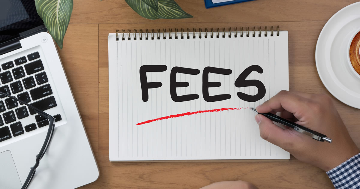 Notebook with handwritten word FEES being underlined in red by man at desk with laptop