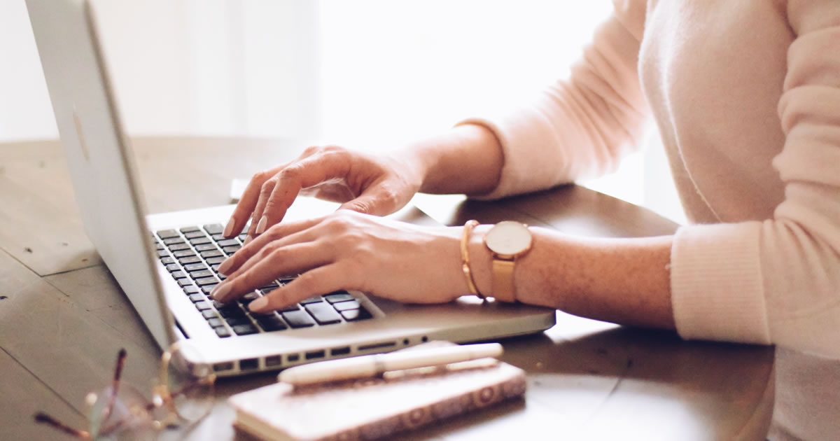 Female's hands typing on laptop at desk