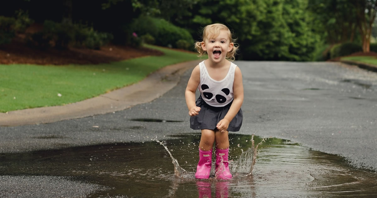Smiling little girl jumping in a puddle