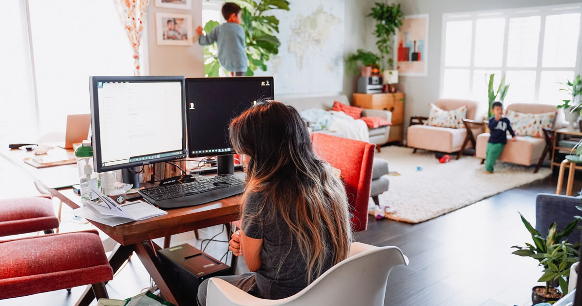 Female writer working from home reviewing websites on dual computer monitors