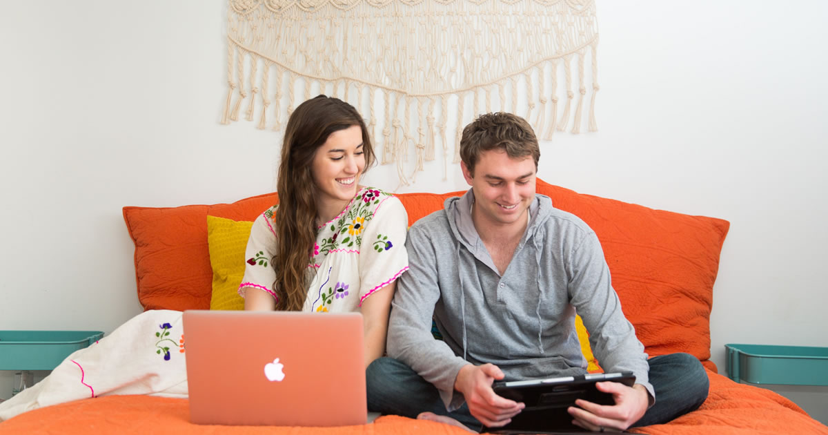 Young couple laughing and watching video on mobile device