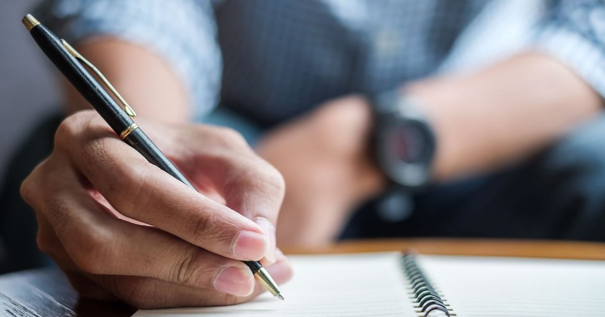 Man writing letter by hand at table