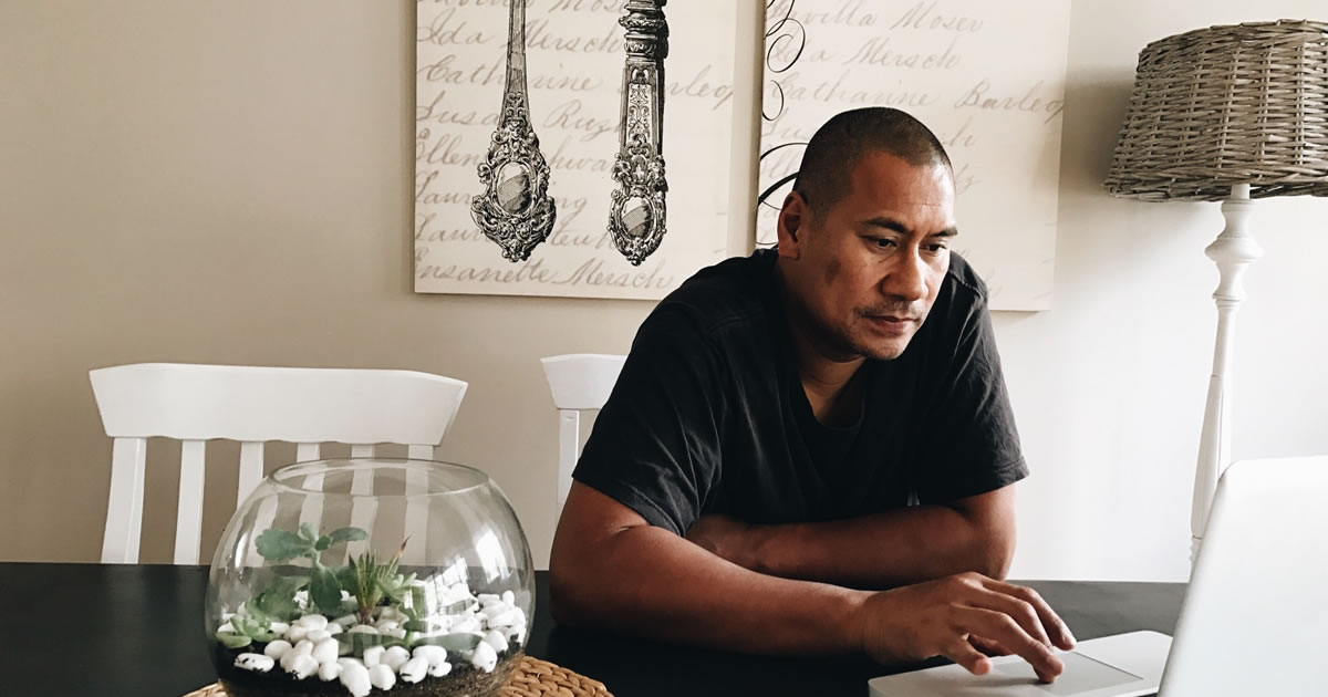 Male writer, sitting at table, reviewing his laptop screen