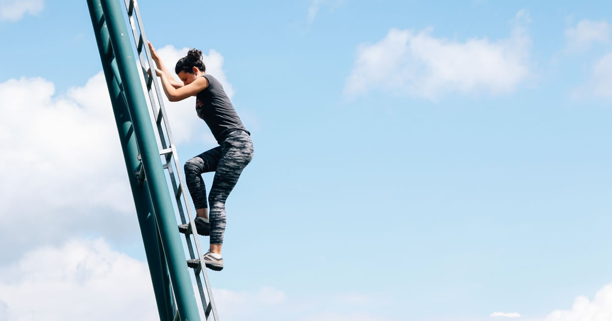 Woman outdoors climbing a metal ladder