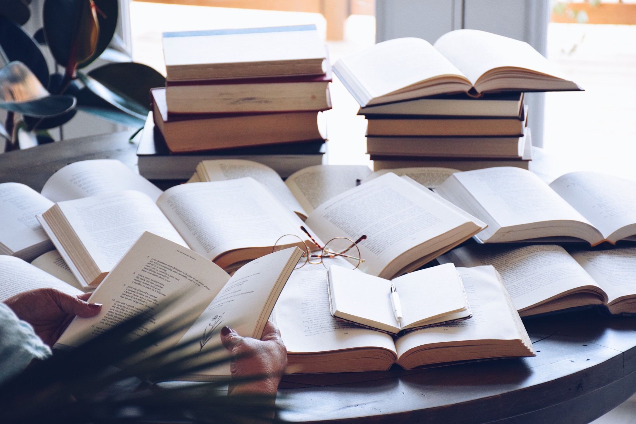 Woman is reading with multiple open books on a table