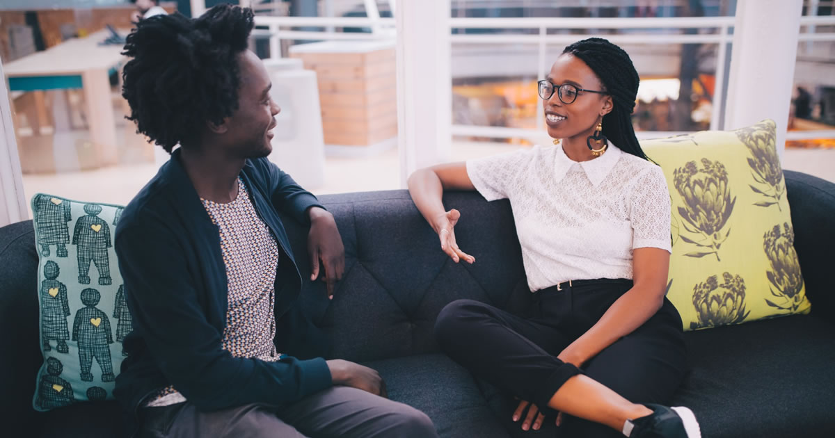 Two business people talking on couch in office