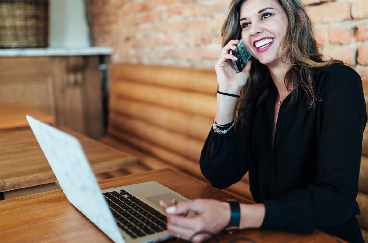 Smiling businesswoman with laptop on her smartphone
