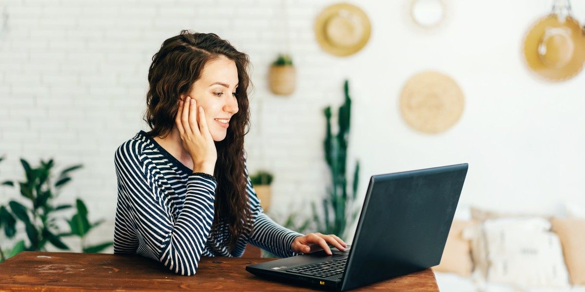 Mulher escrevendo em um laptop em casa