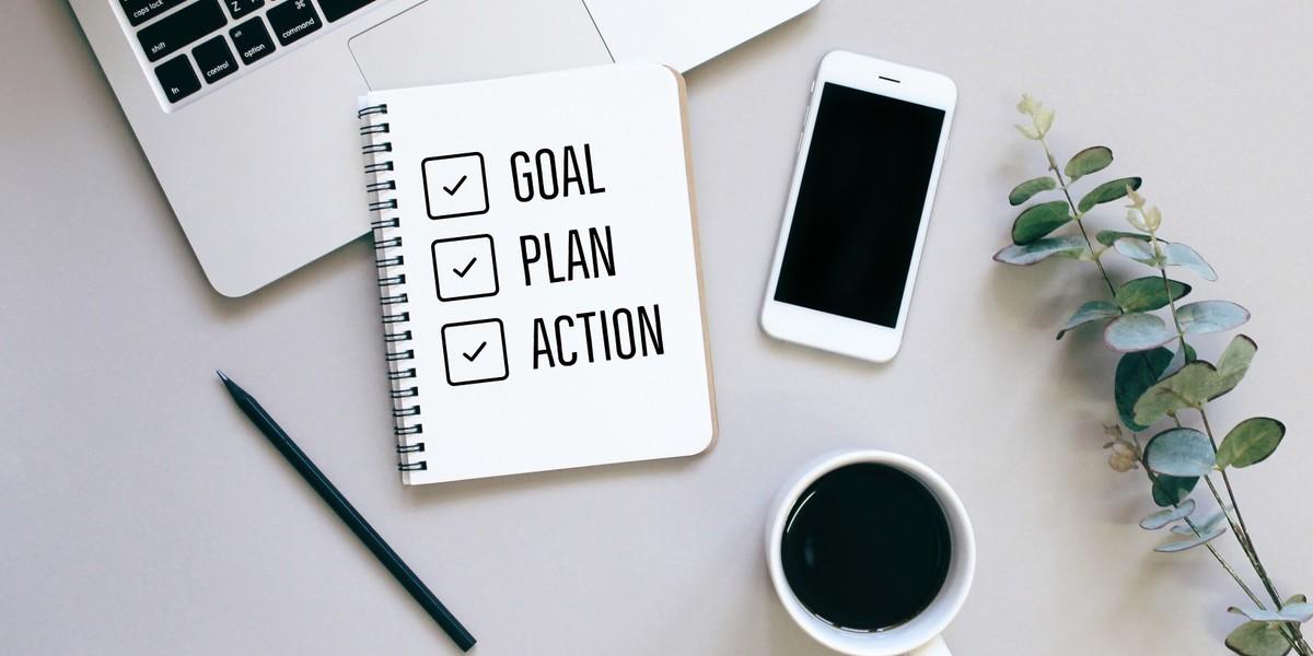 checklist with goal, plan, and action on desk with laptop and smartphone