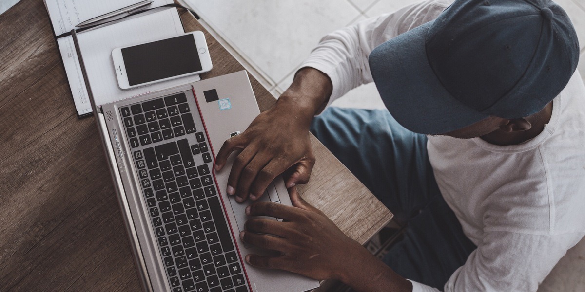 Visão geral de um jovem escrevendo em um laptop em uma mesa