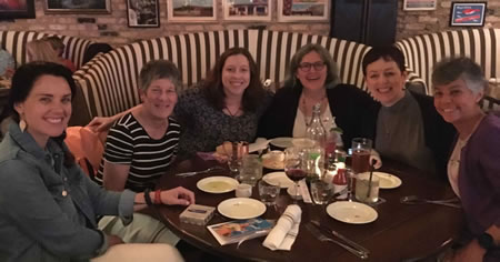 Photo of writer Chris Allsop at a restaurant table celebrating a book launch with fellow AWAI Bootcamp 2019 attendees