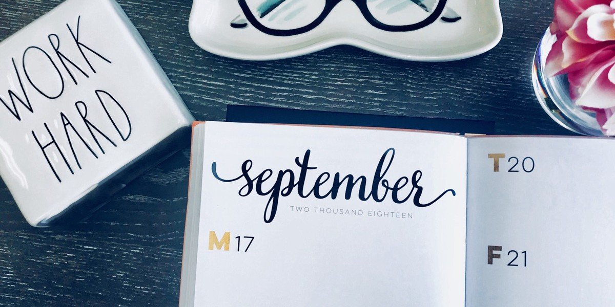 Overhead photo of desk with calendar, glasses, a flower, and the words Work Hard