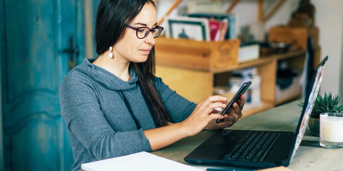 Businesswoman working on smartphone and laptop at desk