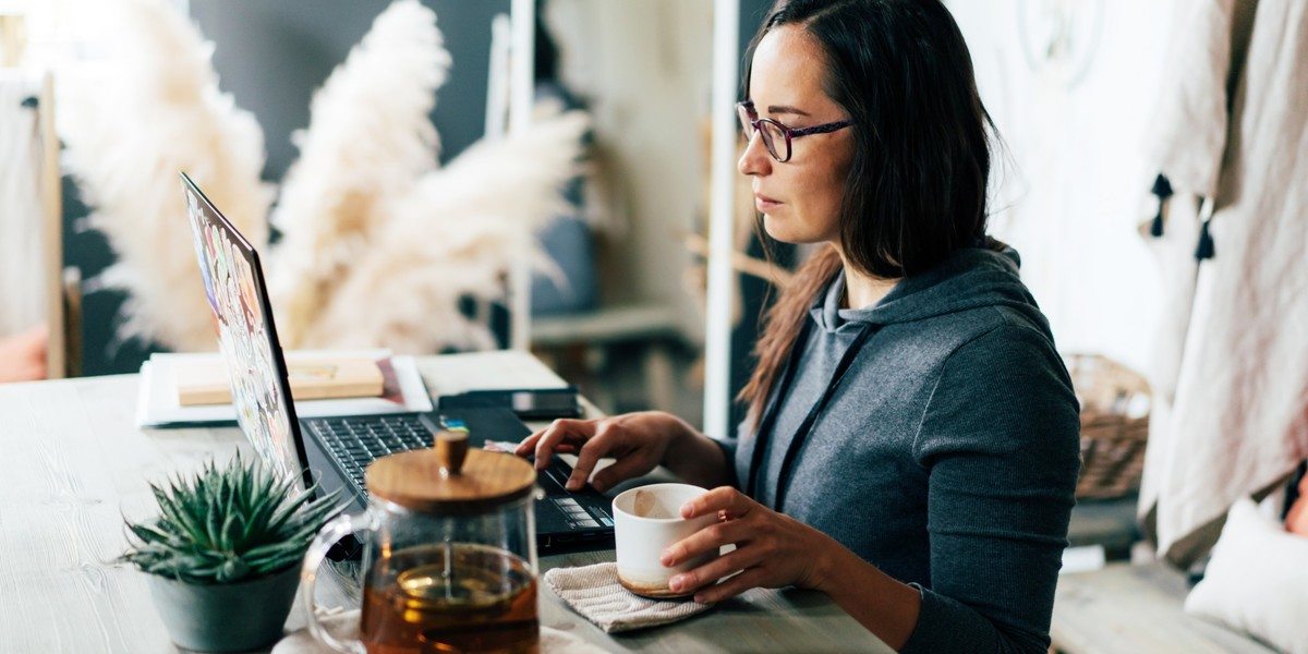 Woman drinking coffee and writing on laptop