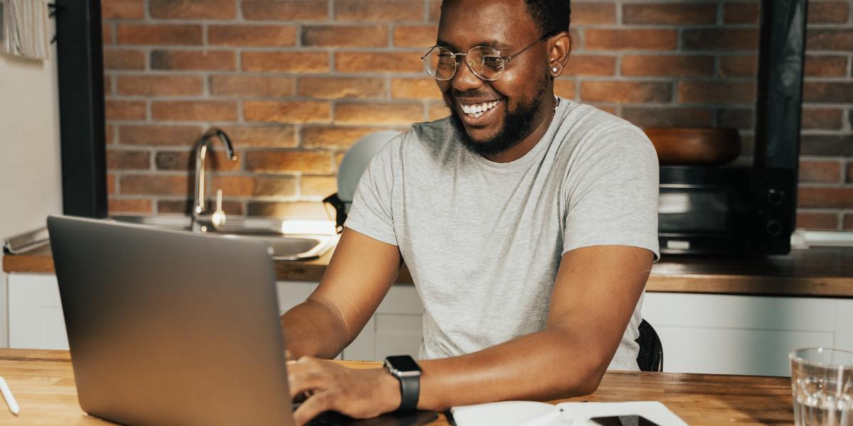 Man smiling and writing on laptop