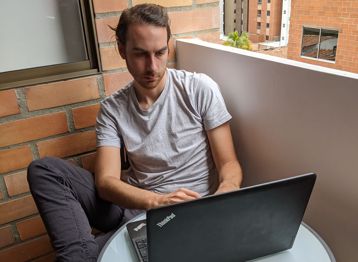 Photo of copywriter Joel Boomer working on his laptop on his home terrace