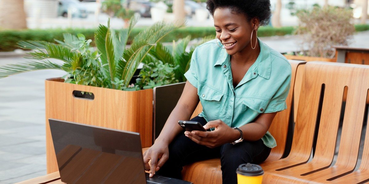 Woman smiling working on laptop and smartphone