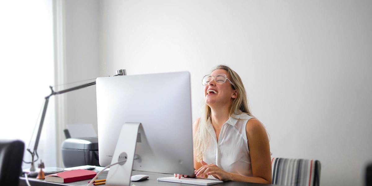 Mulher se divertindo e sorrindo virtualmente conversando com alguém no computador