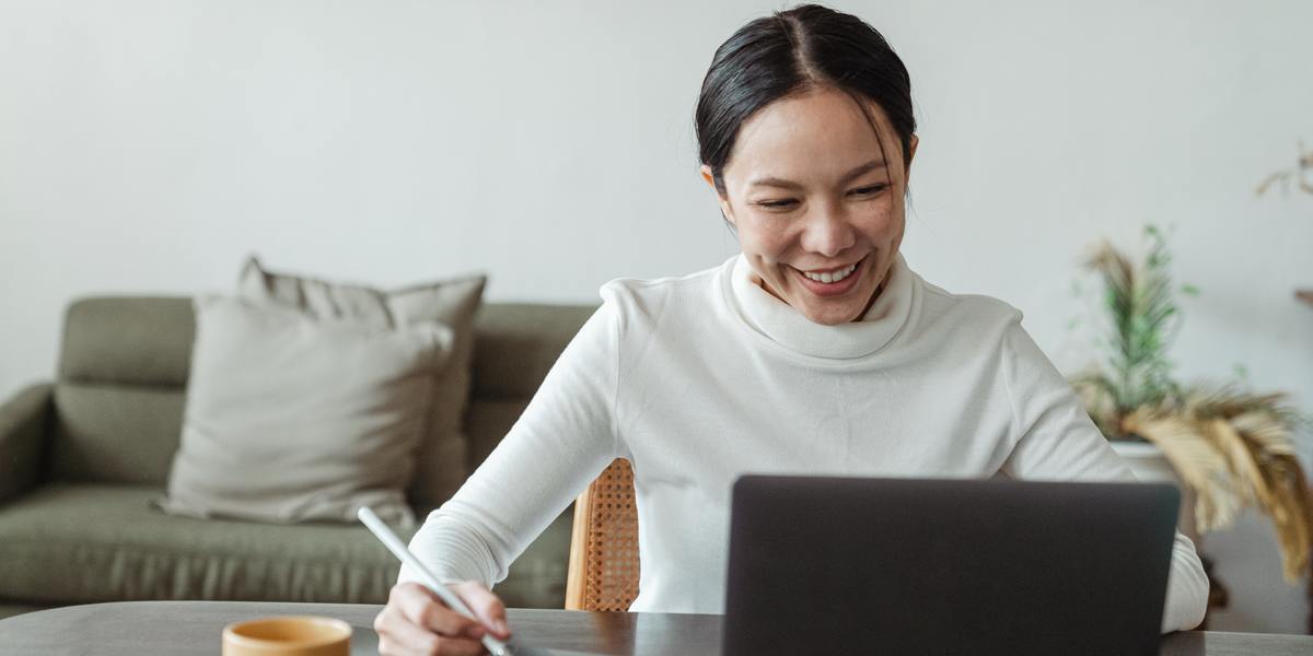 Mulher jovem e feliz digitando em um laptop