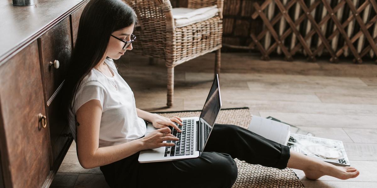 barefoot young lady writing on laptop at home