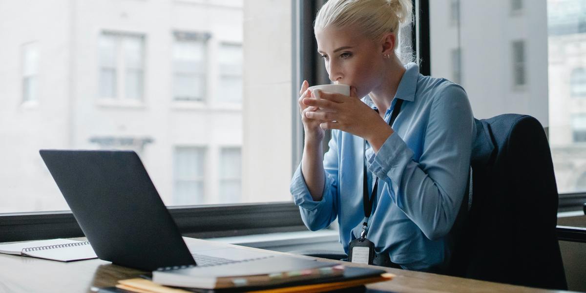 Young business woman sipping coffe and working on computer