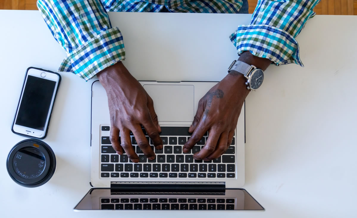 Foto aérea das mãos de um homem trabalhando em um laptop