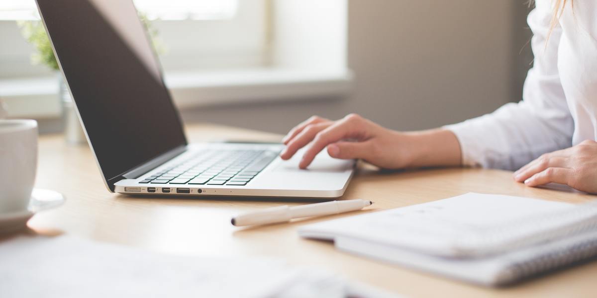 closeup of woman writing on laptop at desk