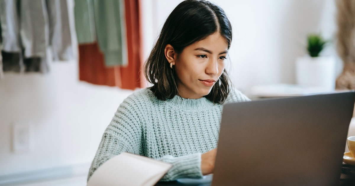 Mulher escrevendo em um laptop em casa