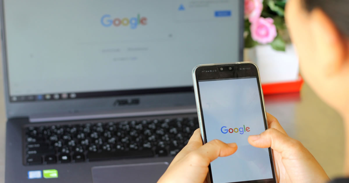 Woman writer looking at Google on smartphone and laptop