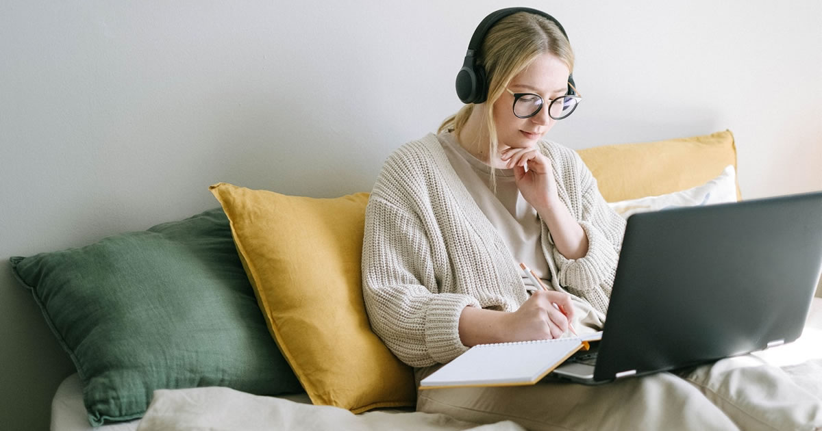 Woman taking notes and working on laptop