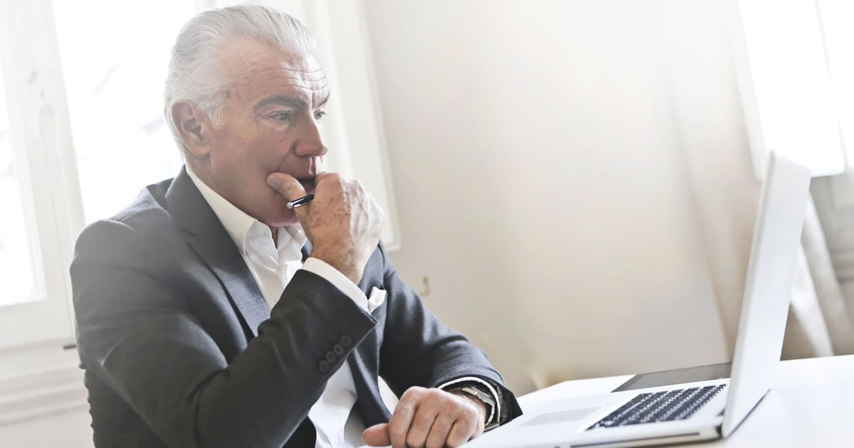 Mature male writer at desk using laptop