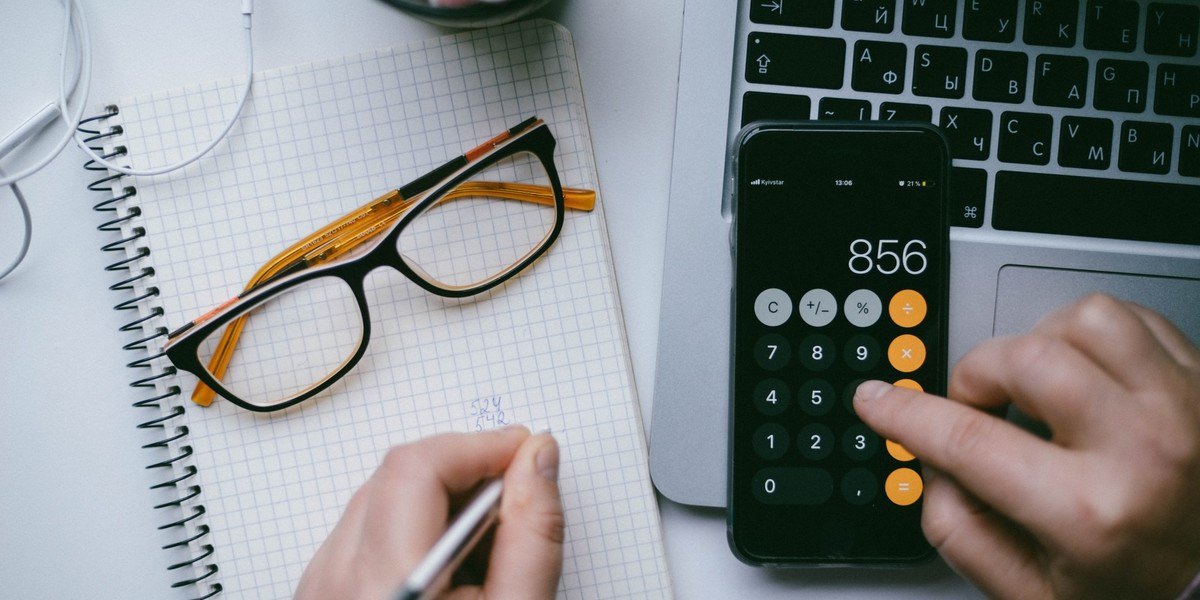 Homem fazendo contas na calculadora do celular