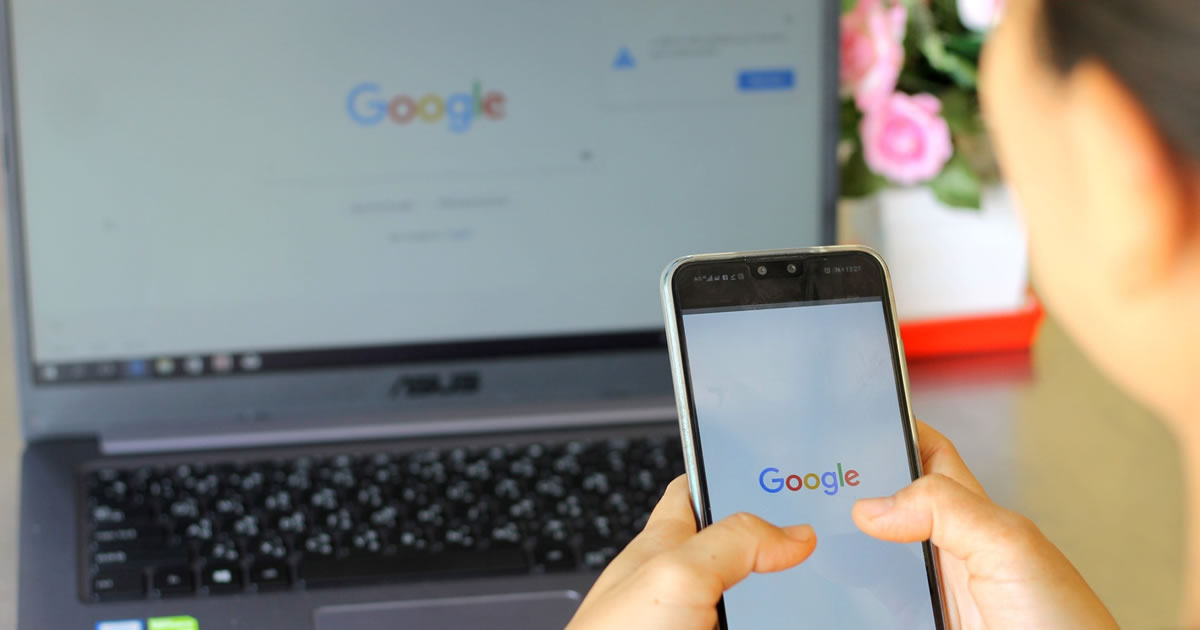 Woman looking at Google homepage on her smartphone and laptop