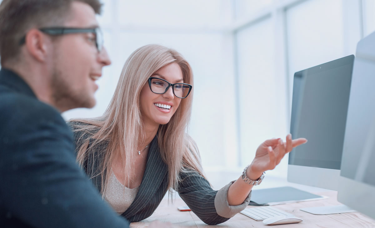 Business colleagues discussing website features sitting in front of a computer