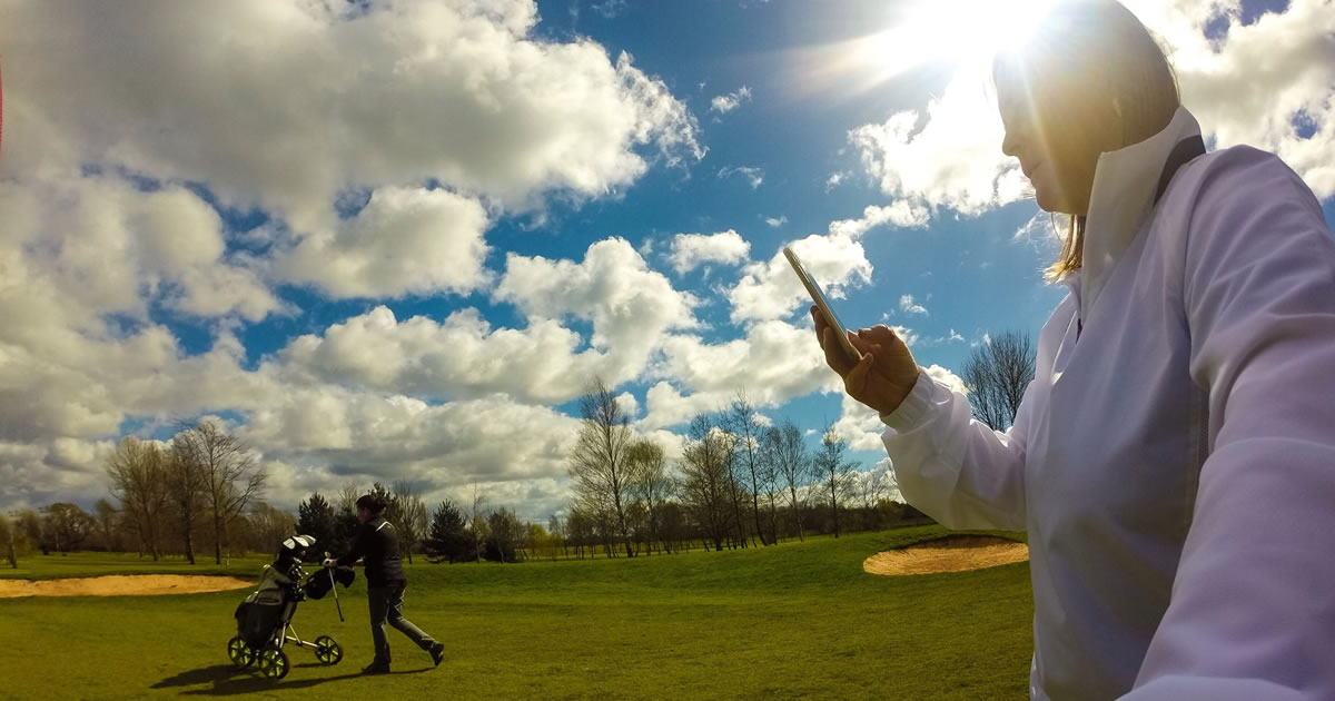 Man looking at smartphone on golf course