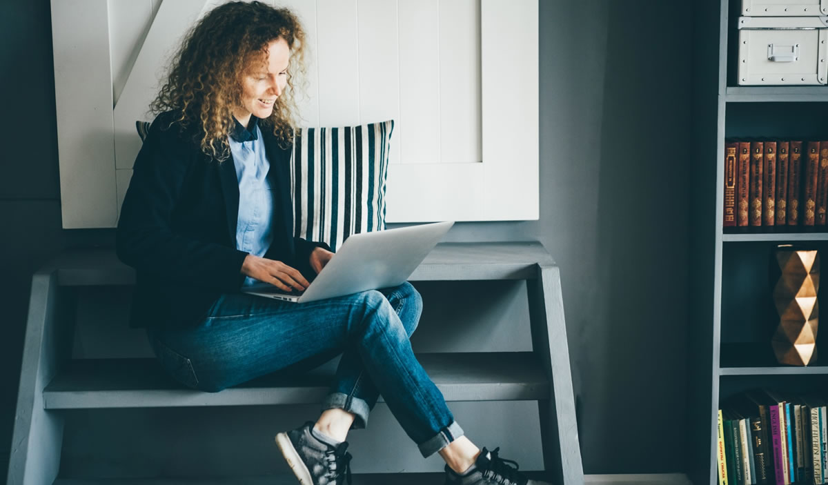 Mulher jovem escrevendo em um laptop em um apartamento