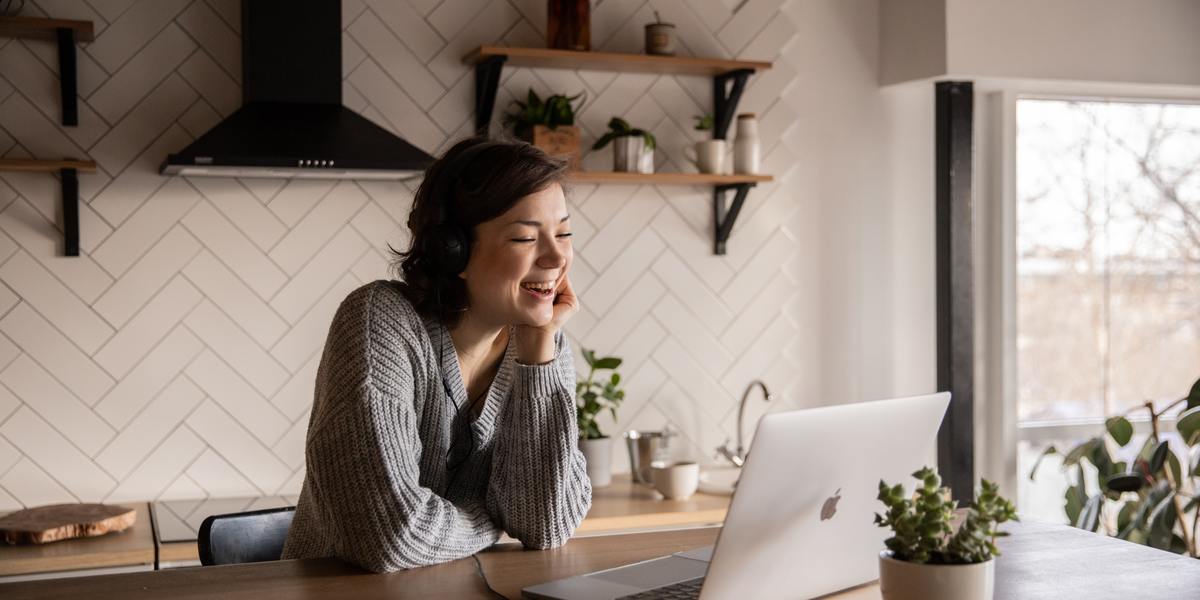 smiling woman watching laptop screen in kitchen