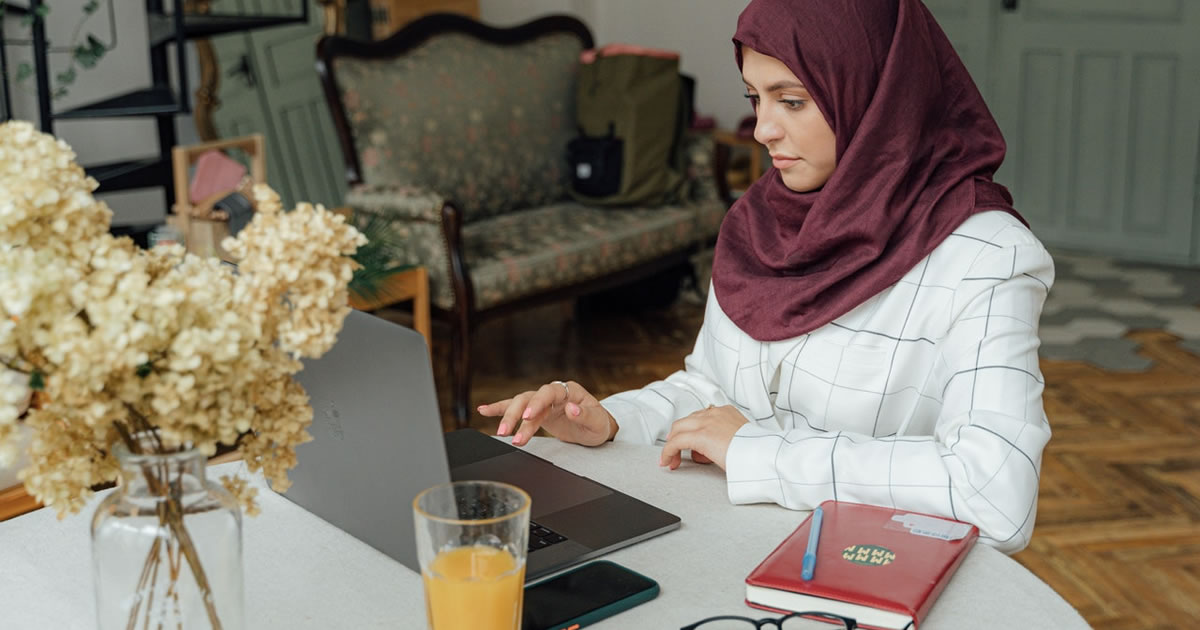 Woman writing on a laptop at a table