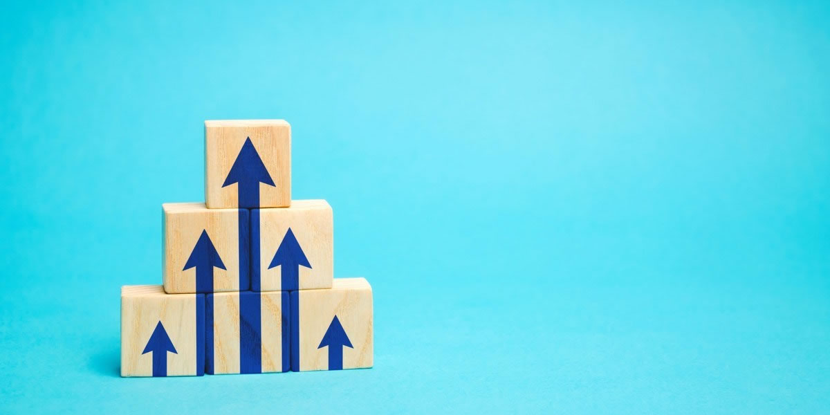 Stack of wooden blocks displaying upward-pointing blue arrows