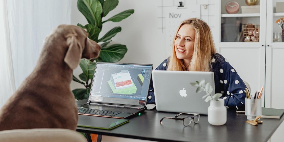 Uma mulher escritora e seu cachorro em uma mesa com um computador