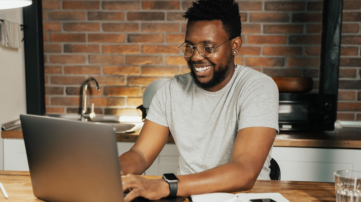 Happy man writing on laptop at table