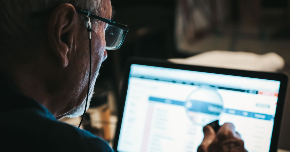 Man researching website on laptop with magnifying glass