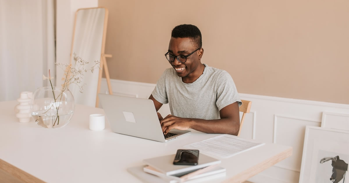 Smiling man writing on macbook air at table