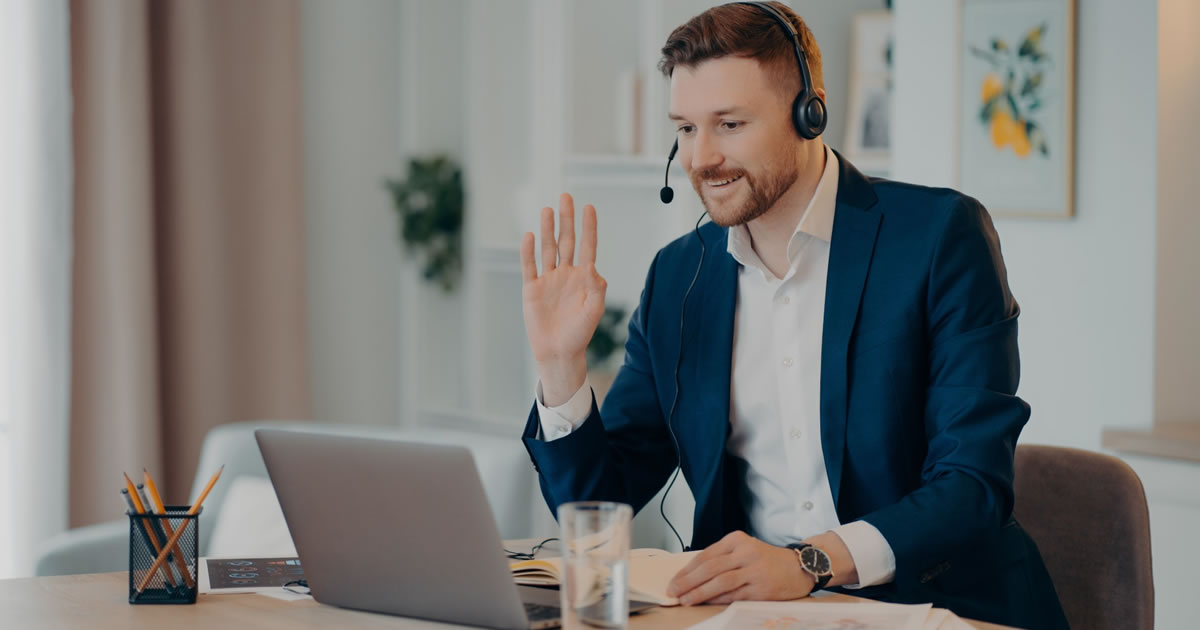 Happy male writer in headset conducting a video interview while working from home