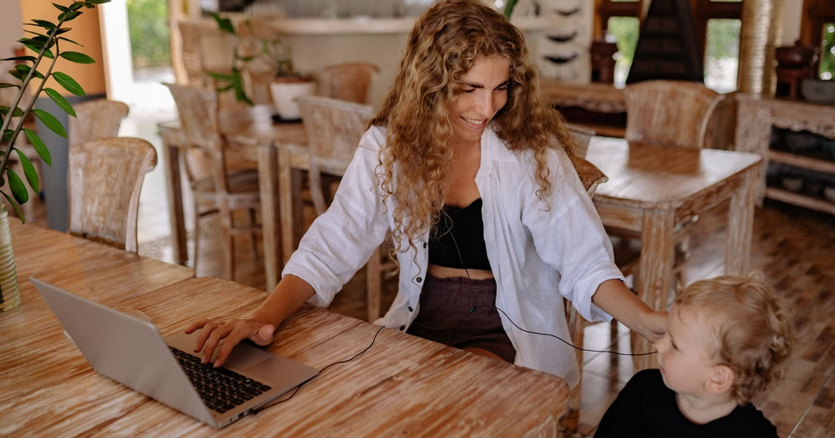 woman smiling at her child while working on her laptop