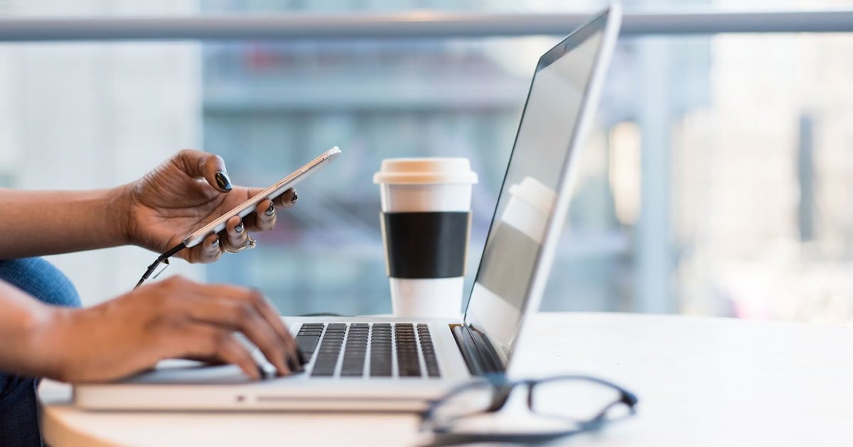 Person reviewing mobile device and laptop